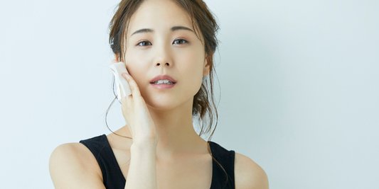 Woman applying natural face toner with cotton pad for gentle, botanical skincare routine